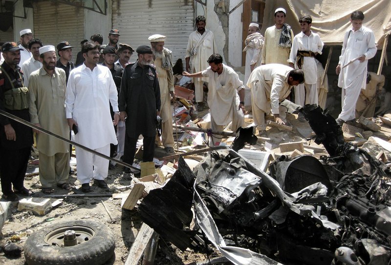 Pakistani investigators search for evidence Thursday, July 26, 2012, at the site of a bomb blast in Khar, Pakistan.

