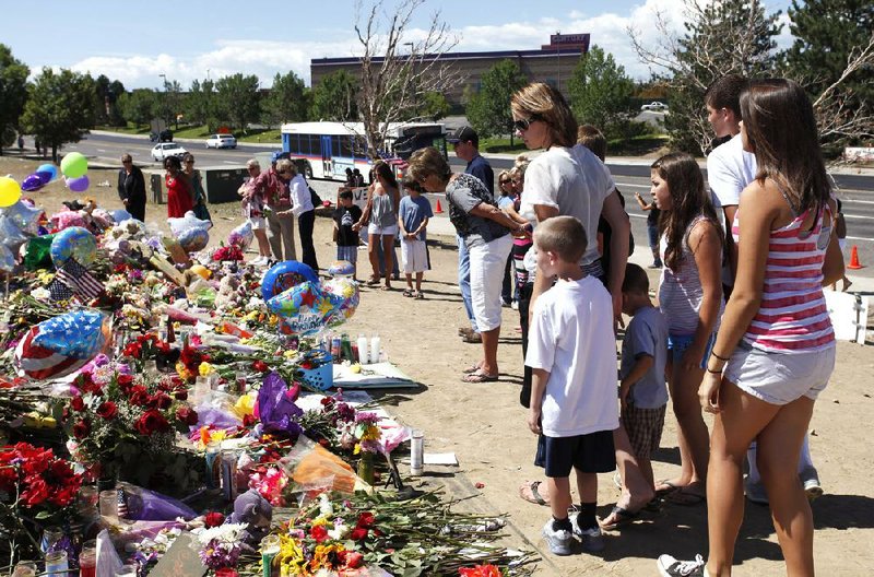 People visit a memorial across the street from the Century 16 theater Thursday in Aurora, Colo. 