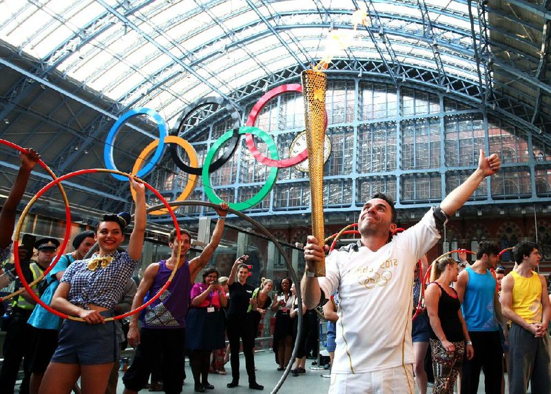 Daniel McCubbin holds the Olympic flame inside the St. Pancras International Railway Station on the 69th day of the London Olympics’ torch relay Thursday in London. 