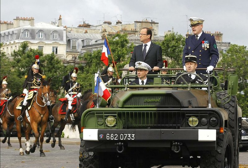 French President Francois Hollande (standing and wearing a suit) alongside French Chief of Staff Admiral Edouard Guillaud review the troops during the Bastille Day military parade July 14. Hollande on Sunday said France must take responsibility for collaborating with the Nazis to arrest and deport 13,000 Jews from Paris in July 1942. 