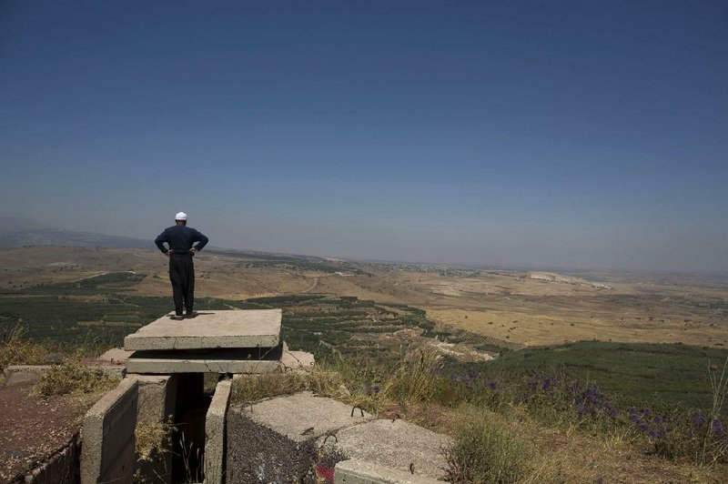 A Druse man looks toward the nearby Syrian village of Jebata al-Khashab from an Israeli army post near the village of Bukata in the Golan Heights. 