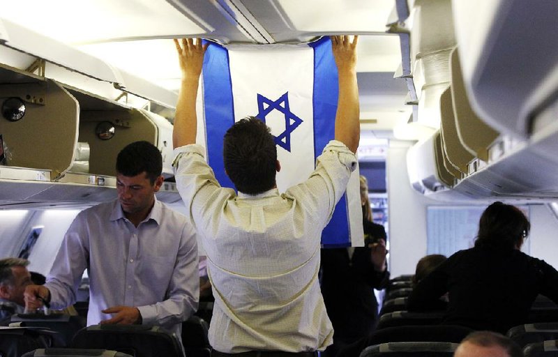 Aide Charlie Pearce examines an Israeli flag Saturday on the charter plane of Republican presidential candidate Mitt Romney as the plane readies to leave London for Israel. 