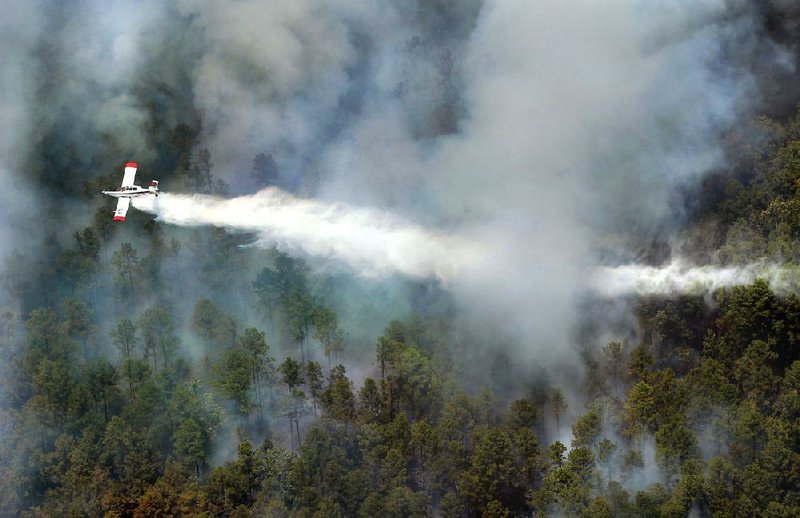 FILE - An Arkansas Forestry Commission single-engine air tanker drops 800 gallons of firefighting foam on a 40-acre wildfire in Roland to assist Lake Maumelle and West Pulaski County fire crews on the ground in this July 24, 2012 file photo.