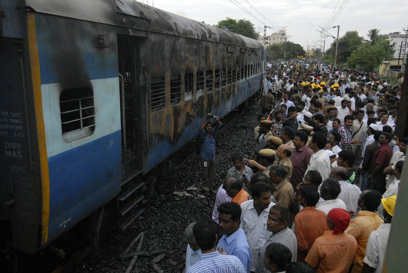 People stand near a charred coach of a passenger train at Nellore, nearly 310 miles south of Hyderabad, India, on July 30, 2012. 