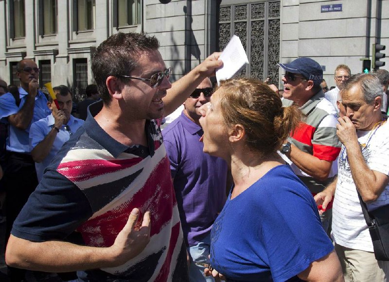 A motorist (right) argues with a demonstrator as transport workers, police and firefighters blocked traffic Monday in Madrid in a protest against government budget cuts. Spain’s recession continued in the second-quarter, the government reported Monday. 