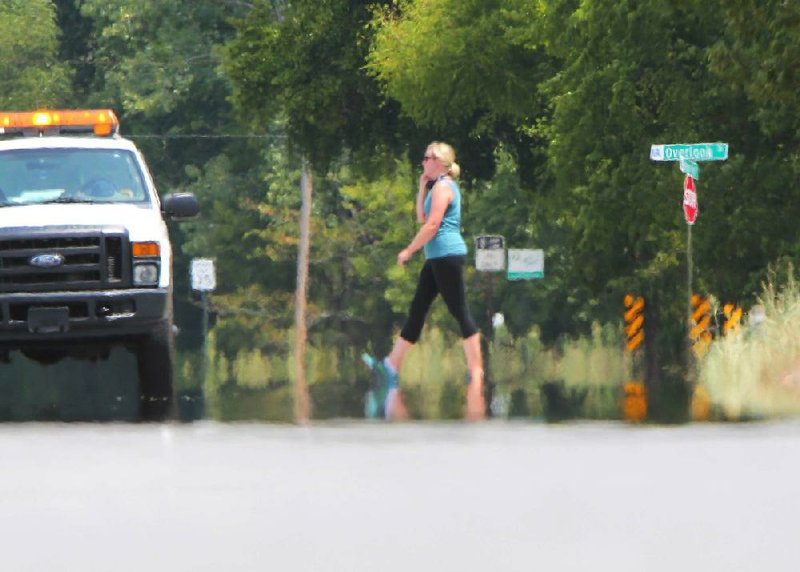 Waves of heat rise off Rebsamen Park Road, blurring a walker in Murray Park in Little Rock on July 30, 2012. (File photo)