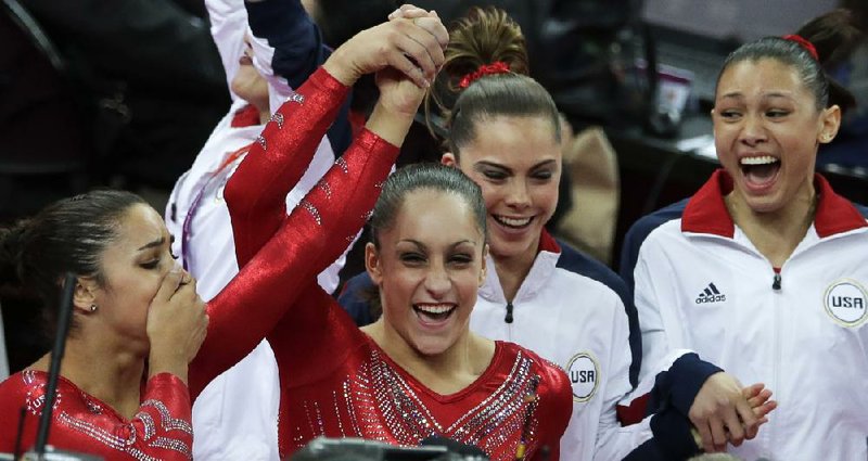 American gymnast Jordyn Wieber (second from left) lifts up the hand of teammate Alexandra Riasman as they celebrate along with McKayla Maroney and Kyla Ross after they won the gold medal Tuesday in the women’s gymnastics team final in London. Video available at Arkansasonline.com/videos. 