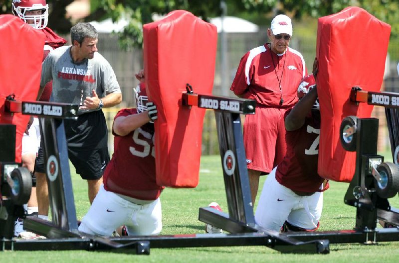 Arkansas Coach John L. Smith (right) and offensive line coach Chris Klenakis (left) watch newcomers during Thursday’s opening day workouts at the school’s intramural fields. 