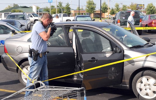 Michael Hendrix, a Springdale police detective, examines a Ford Focus on Friday, Aug. 3, in the Walmart parking lot. 