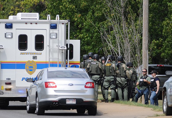 Members of a SWAT team assemble Sunday before entering a house in Fayetteville where they believed a suspect in a shooting might be. A woman was found in the front yard with a gunshot wound to the head.