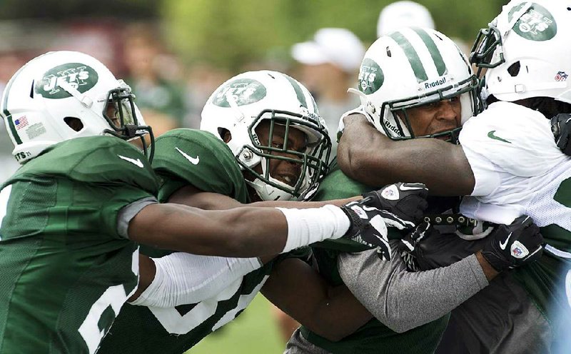 New York Jets cornerback Julian Posey (left), cornerback Donnie Fletcher (34) and safety D’Anton Lynn (second from right) grapple with running back Joe McKnight (right) during a brawl at training camp Monday in Cortland, N.Y. McKnight and Lynn tangled after a play, igniting a short brawl that involved about 20 players. 