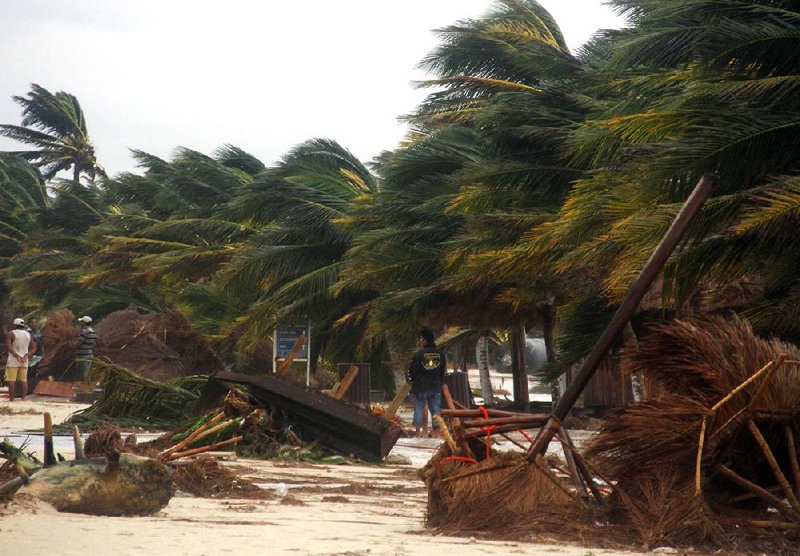 People survey the damage caused by Hurricane Ernesto on Wednesday after it made landfall overnight in Mahahual, near Chetumal, Mexico. 