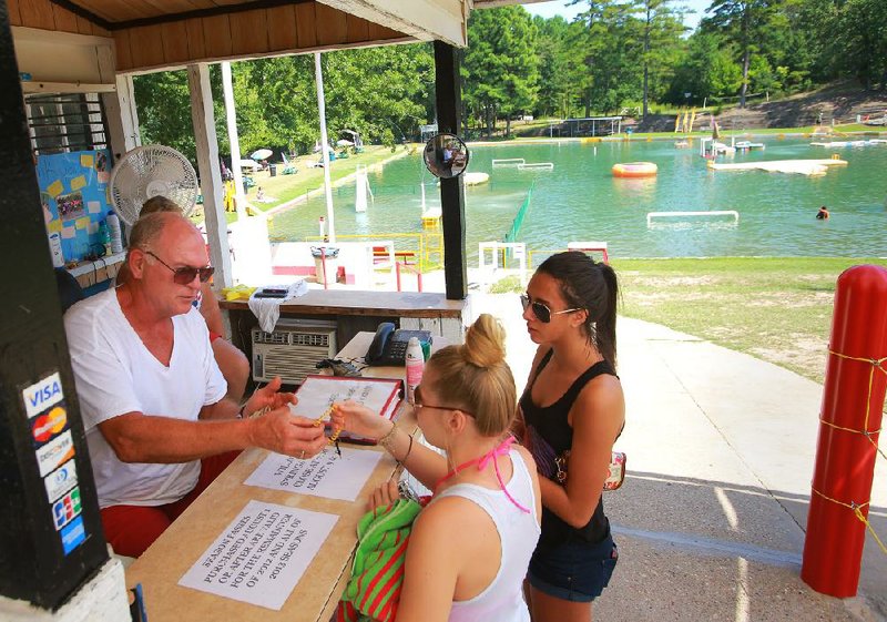 Willow Springs Water Park owner David Ratliff (left) checks in patrons Caitlyn Fite (center) and Jabe Bowen on Thursday afternoon at the park in Little Rock. Video is available at arkansasonline.com/videos. 