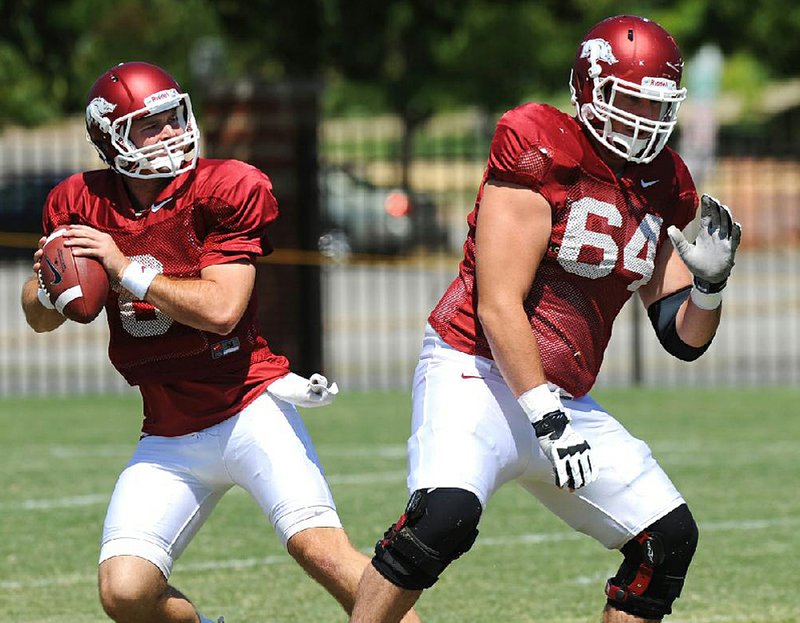 Arkansas center Travis Swanson (64) works on his exchange with quarterback Tyler Wilson during practice.