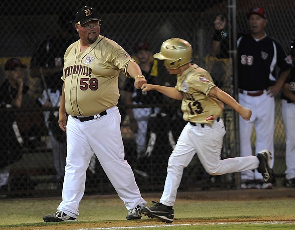Gan Nunnally, left, Bentonville coach, fist bumps David Marts near third base Tuesday after Marts hit a home run during the game against Willamette Valley, Ore., during the Cal Ripken 10-Year-Old World Series at Memorial Park in Bentonville.