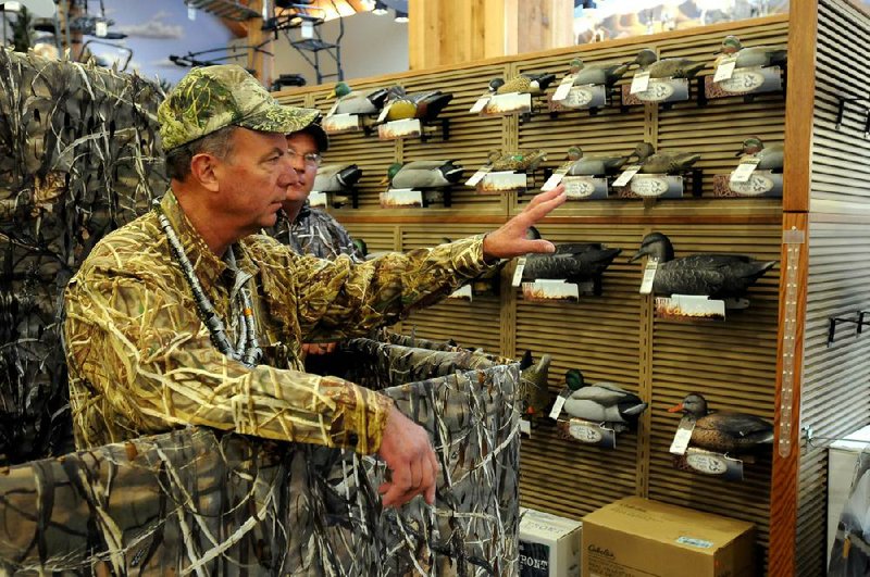 Jerry Dill, sitting in a simulated duck blind, talks about some of the merchandise in the new Cabela’s store in Rogers that’s set to open Aug. 30. 