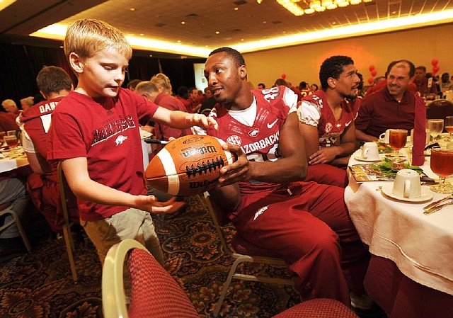 Arkansas junior safety Jerry Mitchell (center) signs a football for 8-year-old fan Payton Patrick of Maumelle on Friday during the annual football kickoff luncheon at the Northwest Arkansas Convention Center in Springdale. 