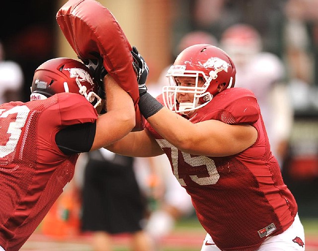 Arkansas sophomore offensive lineman Luke Charpentier (right) works through a drill before Saturday’s scrimmage at Razorback Stadium in Fayetteville. 