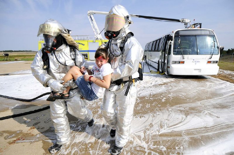 STAFF PHOTO MARC F. HENNING
Firefighters carry Ana Beth La Tour, 13, of Fayetteville to a triage area Saturday, Aug. 18, 2012, during the Tri-Annual XNA Full-Scale Exercise at Northwest Arkansas Regional Airport in Highfill. The multi-agency training exercise simulated an MD-80 passenger airliner crash and included around 50 volunteers from Benton County 4-H and the Civil Air Patrol who played the role of victims.