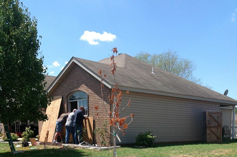 Men board up a window Monday at the house where a woman was killed Sunday.