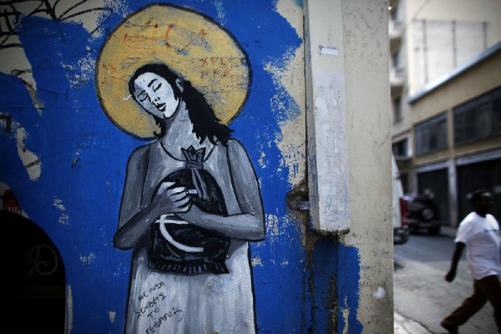 A pedestrian walks past a euro-crisis graffiti mural painted on a wall in Athens, Greece, on Friday, Aug. 17, 2012. Greece's troika of international creditors, the ECB, the European Commission and the International Monetary Fund, will return to Athens in early September to assess progress as the Samaras administration seeks to hammer out 11.5 billion euros in budget cuts for 2013 and 2014. Photographer: Angelos Tzortzinis/Bloomberg
