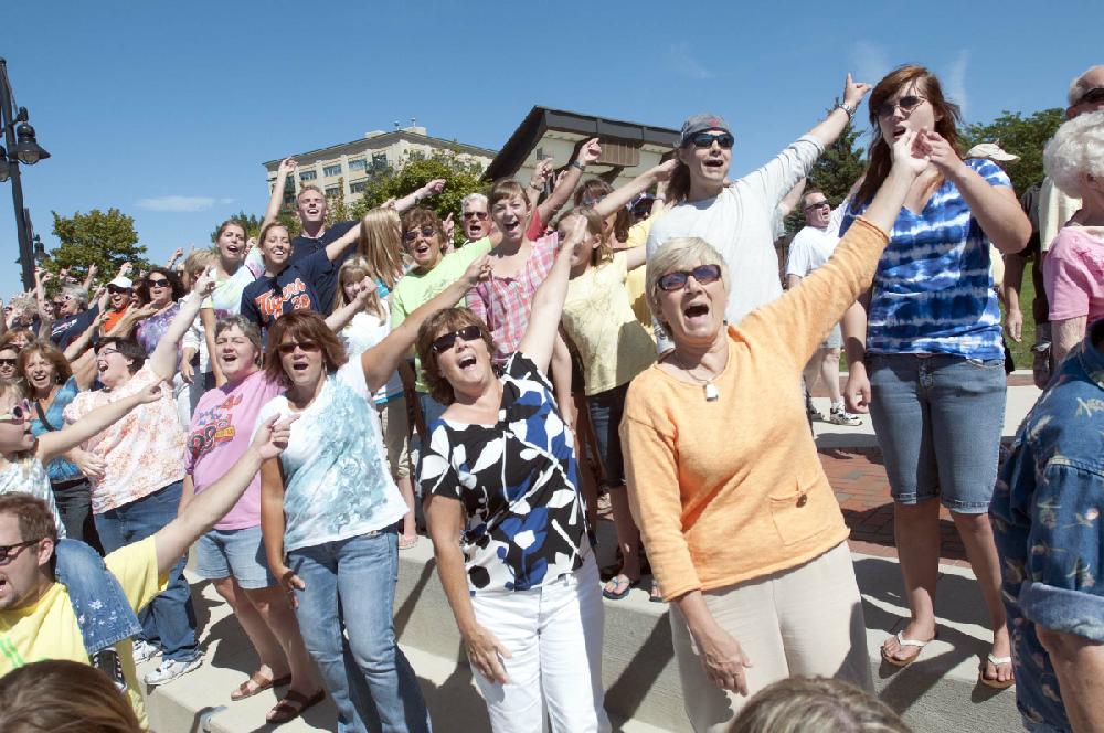 Bay City residents sing and point to downtown Bay City while performing for a video at Wenonah Park in downtown Bay City, Mich., Monday, Aug. 20, 2012. A crew from Status Creative, a Grand-Rapids-based firm, is traveling to 50 cities in Michigan to make a video project that will be promoted by Pure Michigan. (AP Photo/The Bay City Times, Jeff Schrier)