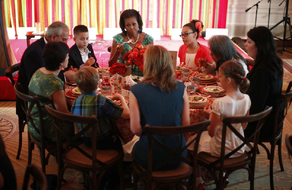 First lady Michelle Obama sits with Michael Prados, left, from Louisiana, and Ilianna Gonzales-Evans, right, from Washington, and others, during the first Kids"State Dinner,"Monday, Aug. 20, 2012, in the East Room of the White House in Washington. (AP Photo/Pablo Martinez Monsivais)