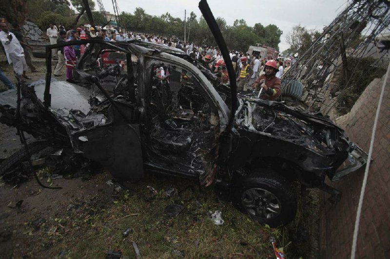 Pakistani officials and rescue workers gather where a suicide bomber rammed a car filled with explosives into a U.S. government vehicle Monday in Peshawar, Pakistan. 