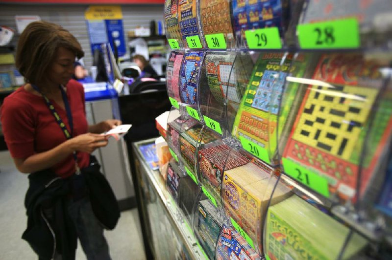 Shay Jones examines her newly purchased lottery ticket Tuesday morning in downtown Little Rock. Ticket sales for the lottery have dropped for the second consecutive month compared with the same months last year. 