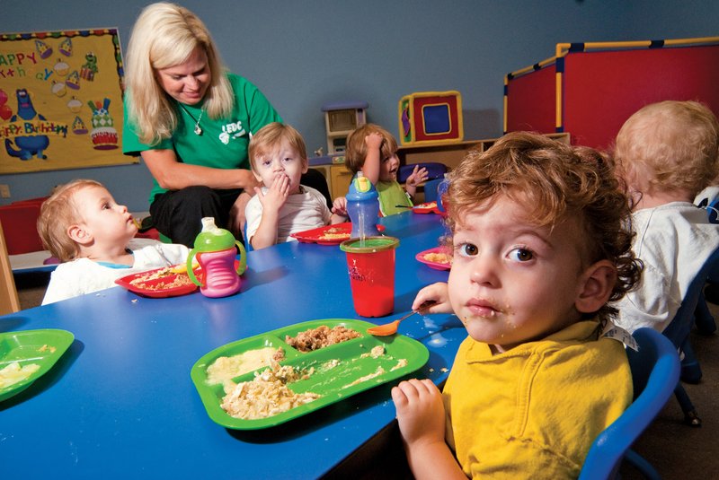 Kullen Henrichs, front, eats lunch as TIna Osburn takes care of the other kids in day care at the Lonoke Exceptional Development Center in Cabot.