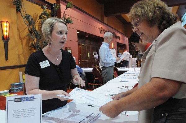 Megan Cuddy, left, with the Rogers-Lowell Area Chamber of Commerce, helps Roberta Moore of Springdale with information Friday at the Northwest Arkansas Job Fair. 