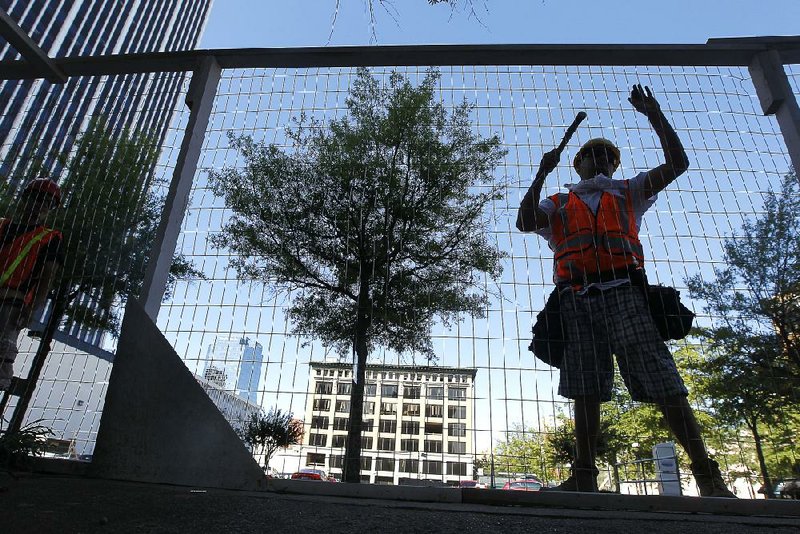 Hernesto Gomez of Scott Construction helps build a fence Tuesday that encircles an entire block of Main Street where a renovation project is under way. 