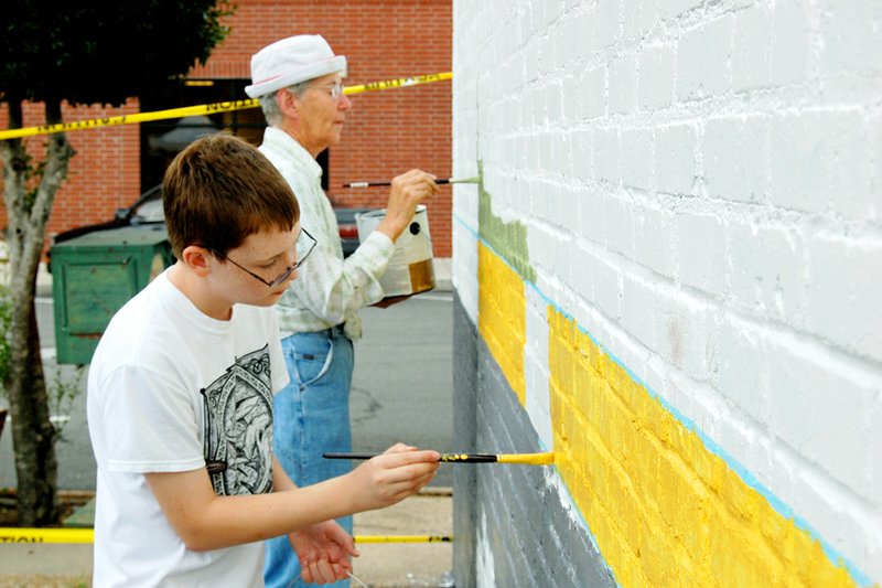 Scott Holbrook and Betty Gentry apply color to the municipal mural being created in Arkadelphia. Clark County residents were invited to paint the background of the artwork that will cover one wall of the Honeycomb Restaurant on Main Street.
