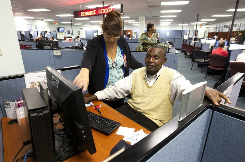 Rose Capote-Marcus works with client Pen Osuji as he completes job applications at the WorkForce One center in Hollywood, Fla. Applications for unemployment benefits dropped by 3,000 last week, the Labor Department said. 