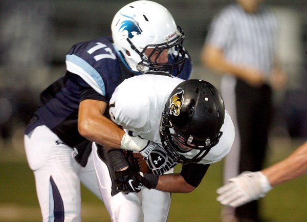 Hunter Patrick, Springdale Har-Ber senior cornerback, grabs Bentonville senior wide receiver Trey Perkins following a reception Friday at Jarrell Williams Stadium in Springdale.