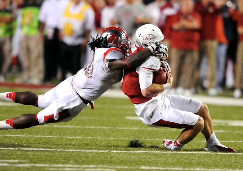 Arkansas quarterback Tyler Wilson (right) is brought down by Rutgers linebacker Khaseem Greene in the fourth quarter of the Scarlet Knights’ 35-26 victory Saturday at Reynolds Razorback Stadium in Fayetteville. Wilson passed for 419 yards but threw two interceptions.