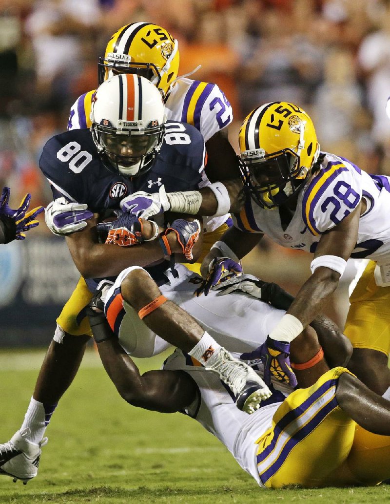 Auburn wide receiver Emory Blake (80) is stopped by LSU cornerback Jalen Mills (28), cornerback Tharold Simon (rear) and linebacker Lamin Barrow (bottom) in the first half of Saturday’s game at Jordan-Hare Stadium in Auburn, Ala. 