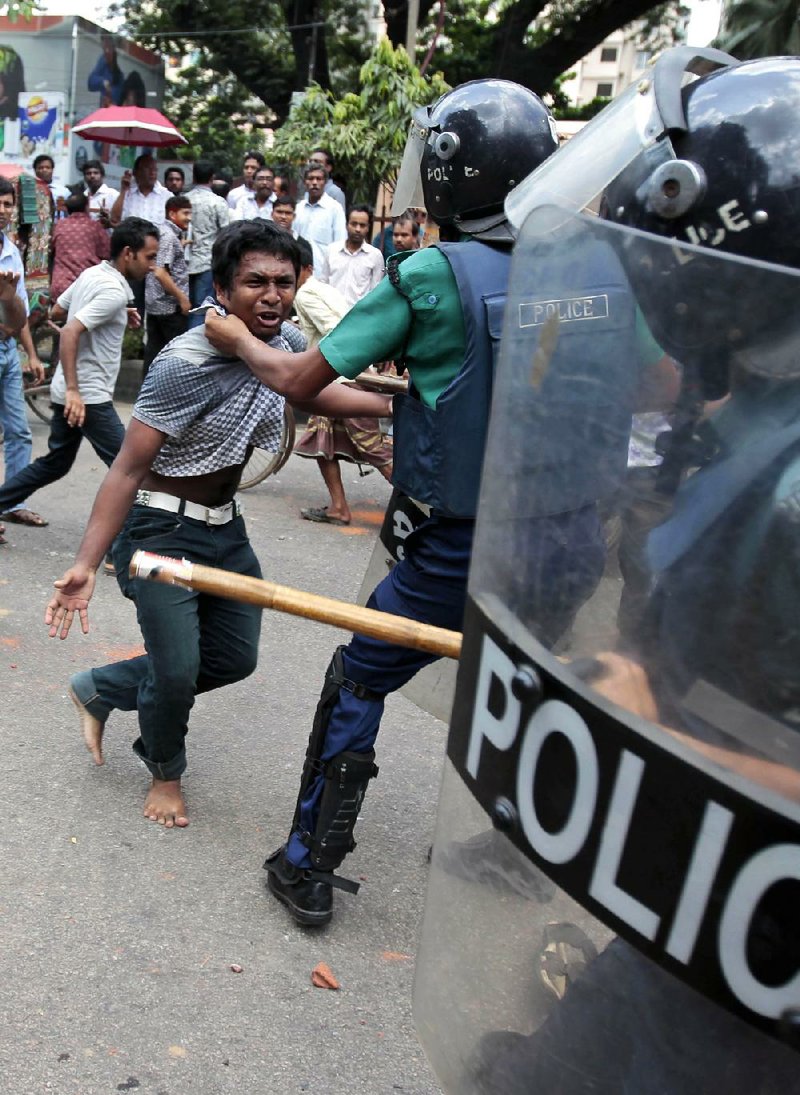 A Bangladeshi policeman grabs a protester Saturday in Dhaka during a demonstration by Islamic groups over a video produced in the U.S. that denigrates the Prophet Muhammad. Protests continued Saturday in Pakistan, where more than 20 people died Friday in clashes with police. 