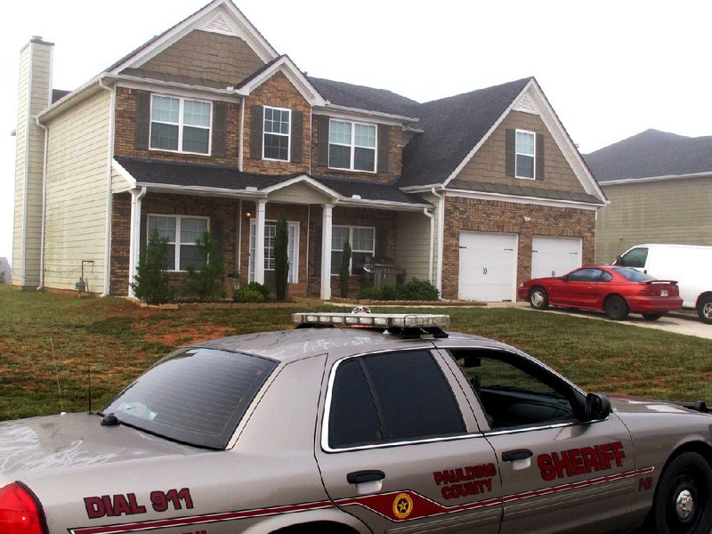 A sheriff’s deputy sits outside the Dallas, Ga., home Friday where authorities say Paul and Sheila Comer kept their son in a bedroom for years before the emaciated teenager was placed on a bus to Los Angeles. 