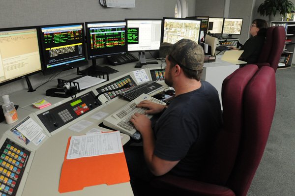 Clayton McDaniel, dispatcher with the Springdale Police Department, works at his station Thursday as fellow dispatcher Kate Morris works at hers at the dispatch center. Matrix Consulting Group recommended the city hire more jailers and dispatchers.
