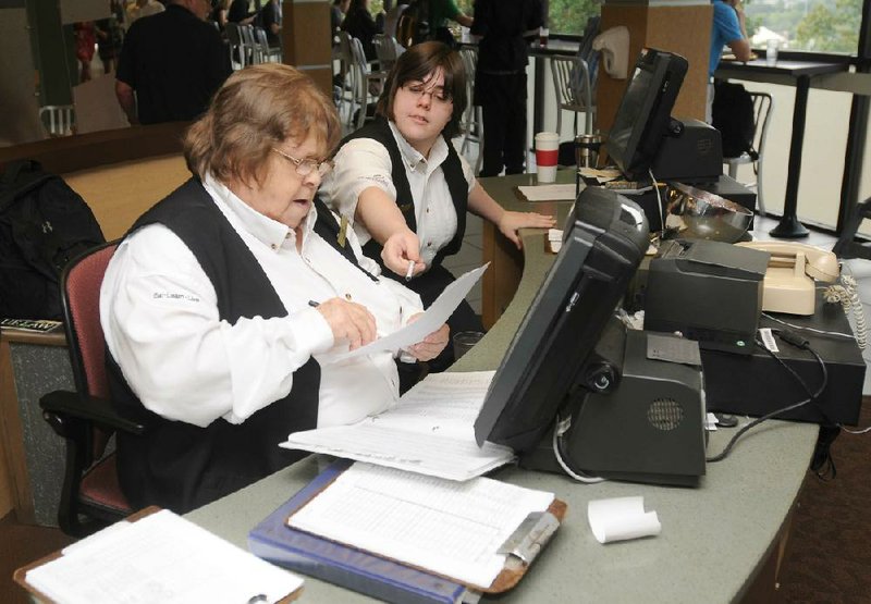 STAFF PHOTO SAMANTHA BAKER
Katie Smith, right, cashier, points out the student identification numbers she checked Monday, Sept. 24, 2012, to Judy Dunaway, cashier, after an unexpected power outage at Brough Commons forced the dining hall to manually list students who came in for breakfast instead of scanning cards on their computers. The outage was caused after an underground power line was accidentally severed by construction crews Monday morning near North McIlroy Avenue and West Dickson Street. Several buildings lost power because of the outage but power was restored approximately an hour later. Some classes and campus activities were disrupted due to the accident.