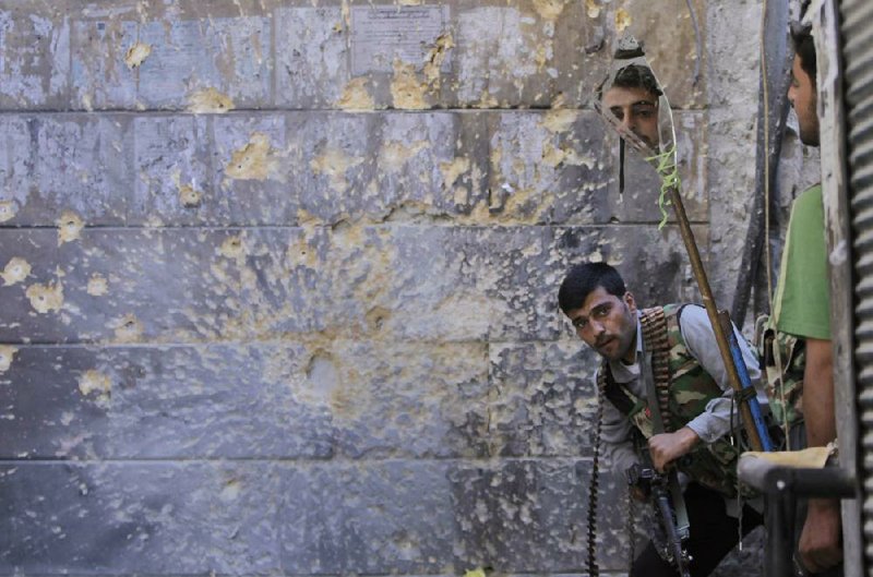 A Free Syrian Army soldier looks around a corner for Syrian troops using a mirror as he and a comrade take position during fighting in Aleppo on Monday. 