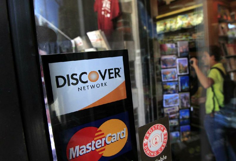 A Discover logo is seen in a window at the entrance of a shop in Cambridge, Mass., on Monday. Discover Bank is paying $214 million to settle charges that it pressured credit-card customers to buy costly add-on services such as payment protection and credit monitoring. 