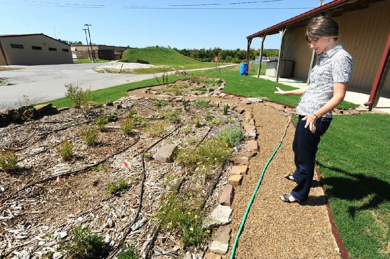 Sophia Stephenson, environmental educator for Washington County’s environmental affairs and recycling division, shows the rain garden Wednesday that was installed at the county’s special waste recycling facility in Fayetteville. 
