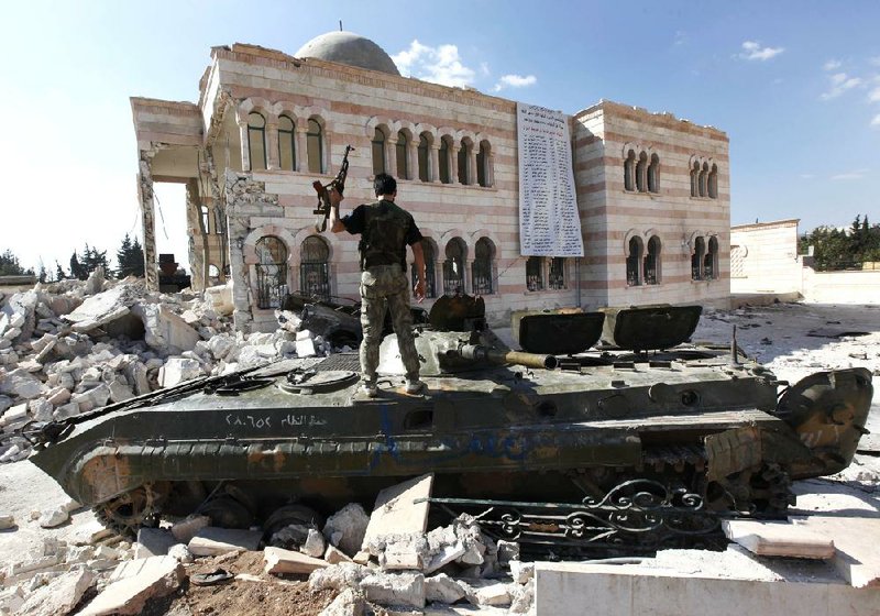 A Free Syrian Army soldier stands on a destroyed Syrian tank in front of a damaged mosque Sunday in the Syrian town of Azaz, on the outskirts of Aleppo.


