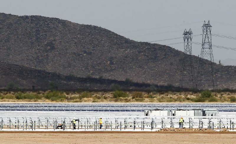 Workers build rows of solar panels at a Mesquite Solar 1 facility under construction last year in Arlington, Ariz. 