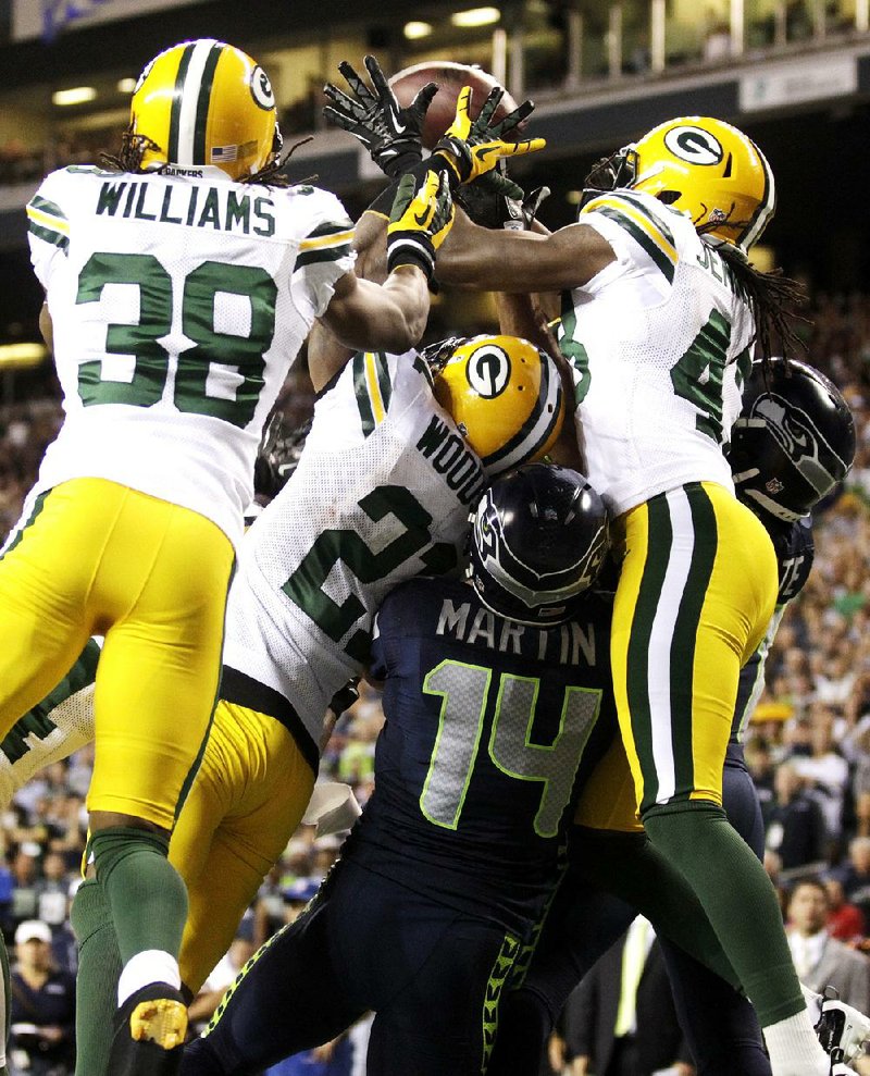 Green Bay defenders Tramon Williams (38), Charles Woodson (21) and M.D. Jennings (43) fight for possession of the jump ball with Seattle receivers Charly Martin (14) and Golden Tate (right) on Monday night. Officials credited Tate with the reception, giving the Seahawks a touchdown and a 14-12 victory. 