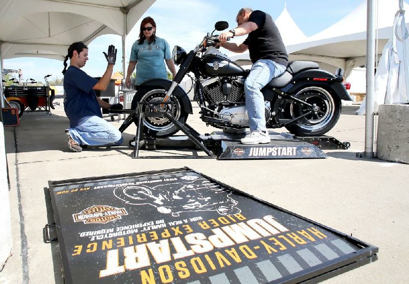 Jon Melham (from left), Sharon Fisher and Duane Gardner help set up a motorcycle ride simulator Tuesday at Baum Stadium off Razorback Road in Fayetteville. It was furnished by Harley Davidson, one of dozens of vendors participating in the 2012 Bikes, Blues and BBQ motorcycle rally, which begins today.