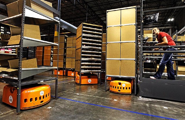 Stacey Pope fetches items brought to her Tuesday by an orange KIVA System robot at a Dillard’s Inc. warehouse in Maumelle. 