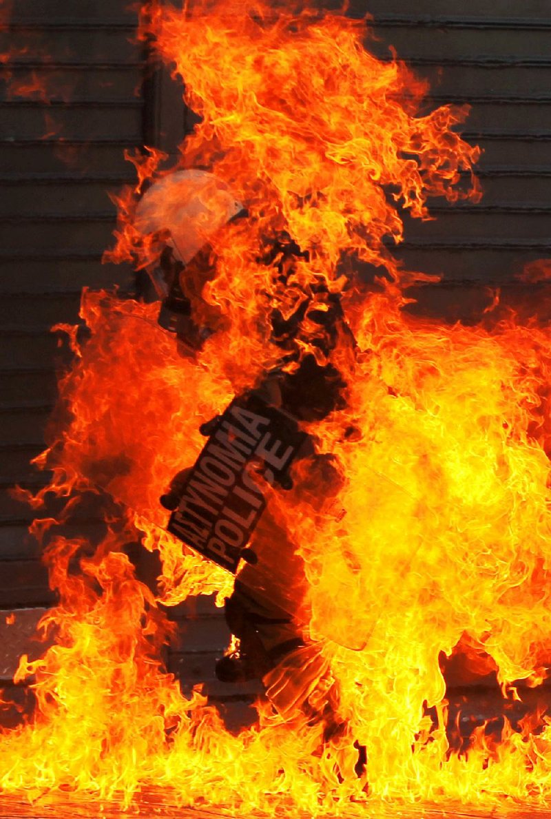 Fire from a demonstrator’s firebomb consumes a Greek riot policeman Wednesday in Athens during a protest near the Parliament building that drew tens of thousands of striking workers. 